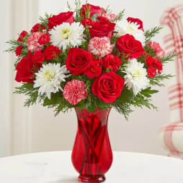 Red roses and white daisies in a red glass vase