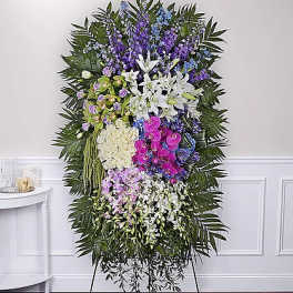 Tall standing floral spray with white lilies, orchids, and purple flowers