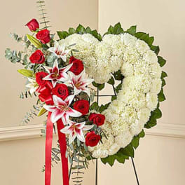 Heart-shaped floral wreath with white blooms, red roses, and lilies