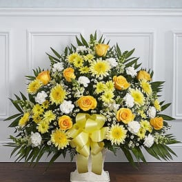 Yellow and white floral standing spray with a ribbon bow