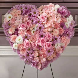 Heart-shaped floral arrangement of pink and lavender flowers on a stand