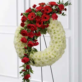 Red and white floral wreath on a black stand