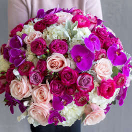 Round bouquet of pink roses, white hydrangeas, and purple orchids