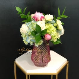 Pink and white roses with hydrangeas in a pink glass vase