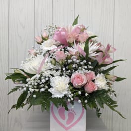 Pink and white floral arrangement in a white box with a pink footprint design
