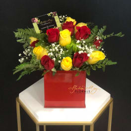 Red and yellow roses in a red square vase