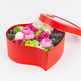 Heart-shaped red box filled with pink and white flowers