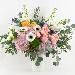 Mixed bouquet of pastel flowers in a white vase