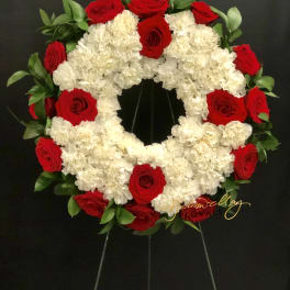 Circular wreath of red roses and white carnations on a black stand