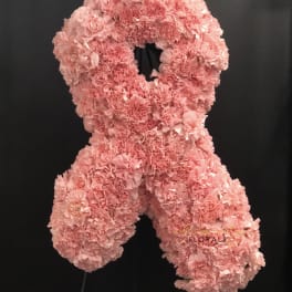 Pink carnation floral wreath on a black stand