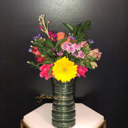 Mixed bouquet in a glass vase with a large yellow daisy and pink flowers