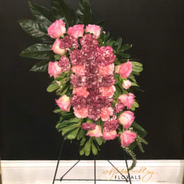 Standing floral spray with pink roses and carnations on a black easel
