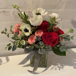 Bouquet of red and blush roses with white anemones in a glass vase