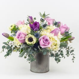 Lavender roses and purple tulips in a ribbed metal vase