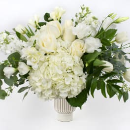 White roses and hydrangeas arranged in a clear vase