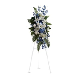 White and blue funeral spray on a white easel