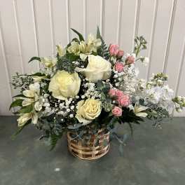 Basket arrangement of cream roses, pink spray roses, and white lilies