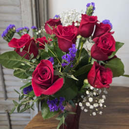 Bouquet of red roses with purple filler flowers in a vase