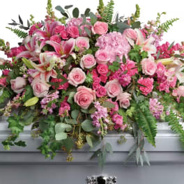 Large pink floral spray with roses and lilies on a casket