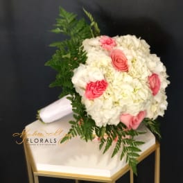 Pink and white bouquet with fern foliage on a white box