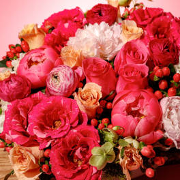 Pink and peach bouquet with roses and peonies on a wooden surface