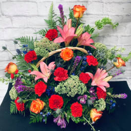 Large mixed floral arrangement with pink lilies, red carnations, and orange roses