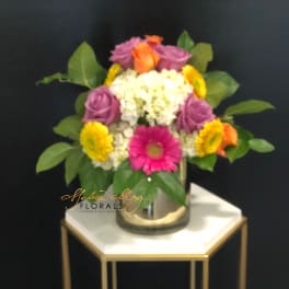 Colorful mixed flower arrangement in a glass vase on a small table