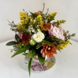 Mixed bouquet with white and pink roses, orange blooms, and yellow filler flowers in a floral vase