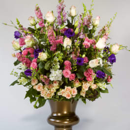 Large mixed bouquet of pink, white, and purple flowers in a bronze vase
