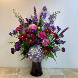 Mixed bouquet in a dark vase with pink roses and purple flowers