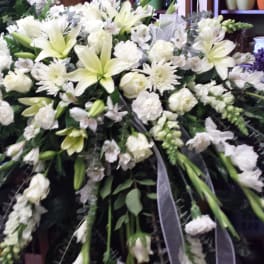 Large white funeral spray with lilies, roses, and carnations