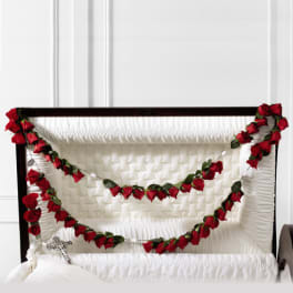 White casket with red rose garlands draped across the top