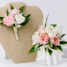 Pink and white rose corsage and boutonniere with ribbon on display