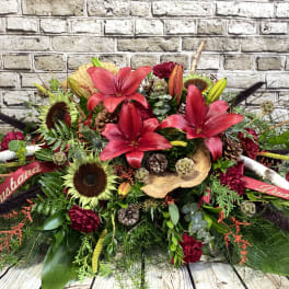 Large red floral arrangement with lilies and sunflowers, accented by ribbons