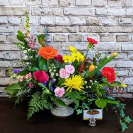 Colorful mixed flower arrangement in a white pedestal vase