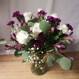 Bouquet of white roses, purple carnations, and alstroemeria in a glass vase