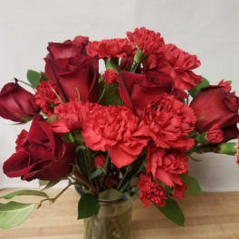 Red roses and carnations in a clear glass vase