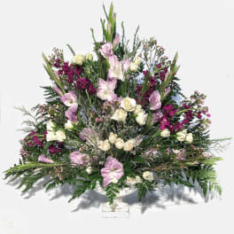 Fan-shaped arrangement of white spray roses and lavender flowers in a white pedestal bowl