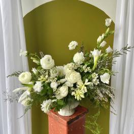 White floral arrangement in a white vase on a pedestal