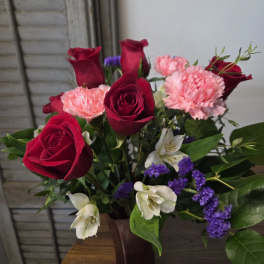 Bouquet of red roses, pink carnations, and white flowers in a vase