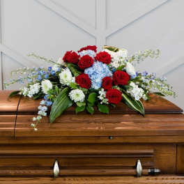 Red roses and blue-white flowers arranged on a casket