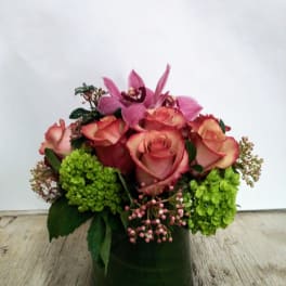 Pink roses and orchids arranged in a green vase