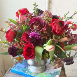 Bouquet of red roses and purple orchids in a silver vase