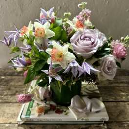 Bouquet of lavender roses and mixed spring flowers in a green vase