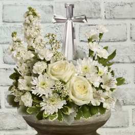 White floral arrangement in a basket with a silver cross topper