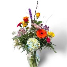 Mixed bouquet in a clear glass vase with bright roses and daisies