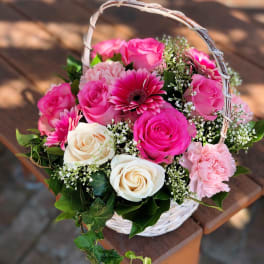 Pink and white roses with gerbera daisies in a white basket