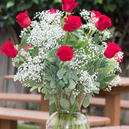 Red roses arranged with white baby's breath in a clear glass vase