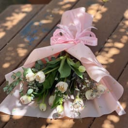 Bouquet of white tulips wrapped in pink paper with a ribbon