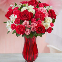 Bouquet of red, pink, and white roses in a red glass vase